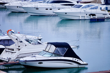 Yachts and speed boats at harbor. Yachts moored in the port. Ocean Coast pier. High class lifestyle. Yachting. Expensive toys. Sea ​​transport. Nautical. Yachting sport. Expensive yachts at the pier.