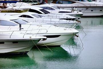 Yachts and speed boats at harbor. Yachts moored in the port. Ocean Coast pier. High class lifestyle. Yachting. Expensive toys. Sea ​​transport. Nautical. Yachting sport. Expensive yachts at the pier.