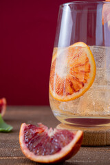 Fresh, cool orange lemonade made from fresh oranges. Natural lemonade based on orange juice without sugar. copyspace. Homemade red orange lionade on a bright burgundy, red background.