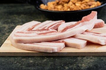 a close up of food on a cutting board near a frying pan