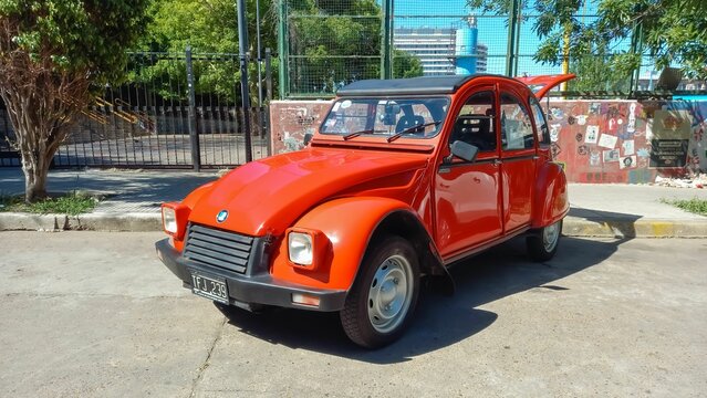 old red Citroen IES 3CV America 1986 parked in the street. Trees in th background. Classic car show