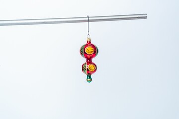Festive Christmas tree ornament is suspended from a hook on a pole on the white background