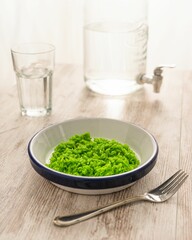 Green rice with water on a table