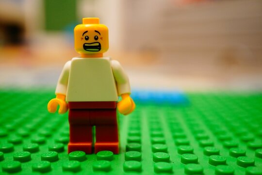 Lego figurine standing on green grass, exhibiting a shocked facial expression