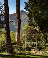 Ornate gazebo stands in the center of a picturesque garden, surrounded by lush green trees