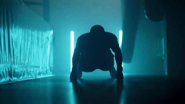 Slow motion video of a man doing push ups in a boxing gym with blue neon illumination