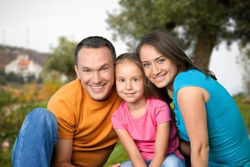 Happy young parents with cute child walking outdoors