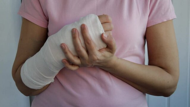 Close-up of a woman's broken arm in a plaster cast, shaking in pain.