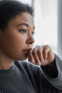 Frustrated Multiracial Woman In Knitted Sweater Looking Away At Home.