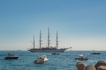 Several boats in the open ocean with rocks in front of them