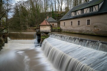 Tranquil outdoor scene featuring a lush green landscape with tall trees and a cascading waterfall