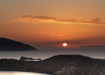 Sunset over some mountains and water with a sunset in the distance