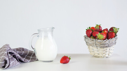 Lactose-free milk in a glass jug and strawberries.