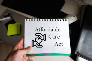 Affordable care act word on notebook holding man against desktop.