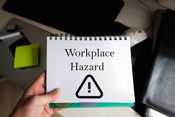 Workplace hazard word on notebook holding man against desktop.