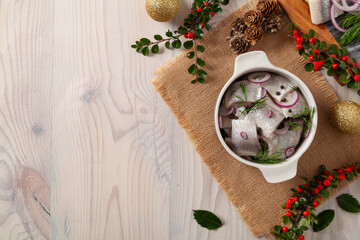 Herring fillets in oil. Served with onion in a bowl. Wooden background.