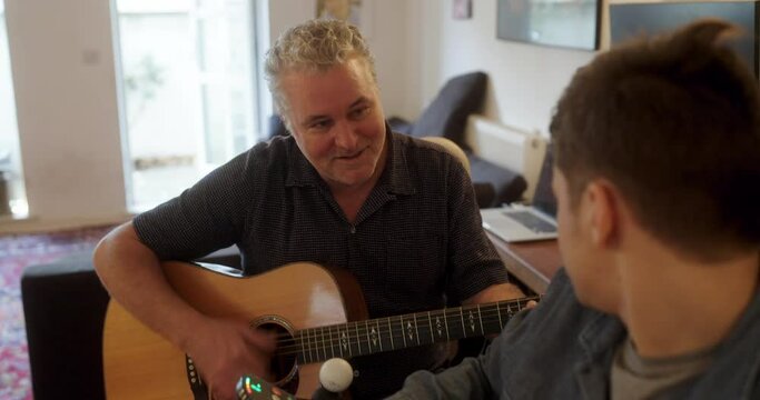 MS PAN Father playing guitar with disabled son at home