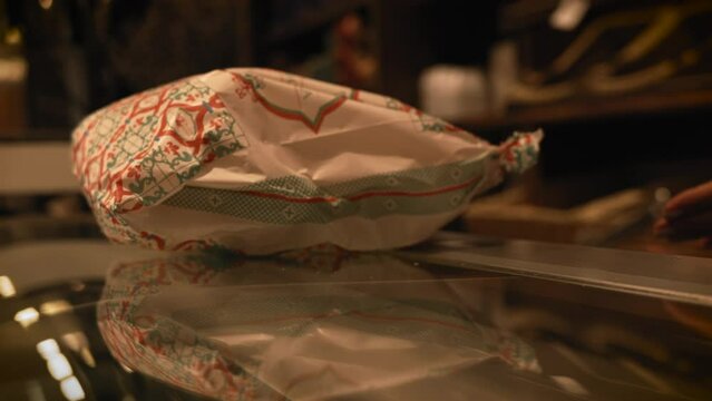 Closeup of a customer giving a paper bag with fresh bread bakery in the market