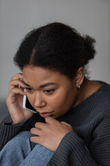 Fototapeta na wymiar Young multiracial woman with depression calling in helpline at home.