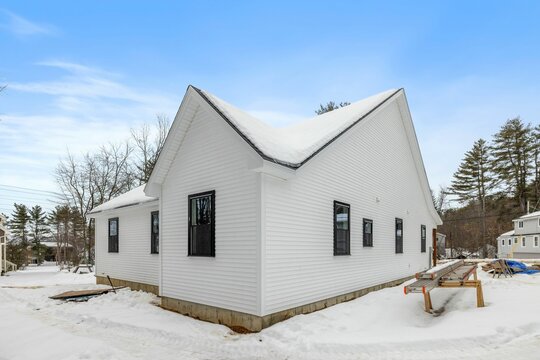 Picturesque white house with a wintery backdrop, surrounded by snow-covered grounds