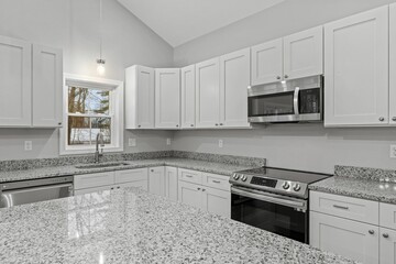 Modern white kitchen with a stainless steel oven and microwave installed on the countertop