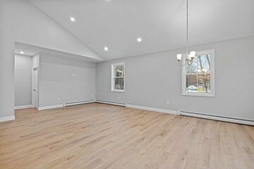 Empty room with wood floors and a hanging lamps in front of a window