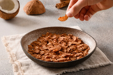 Coconut chips with cinnamon powder in child hand on gray background. Sri lankan vegan sugar free snack for children. Close up.