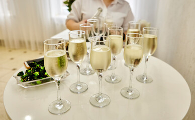 The waitress distributes sparkling white wine to the guests.