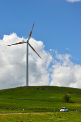 wind turbines among the green hill pastures in the clouds and wind of spring