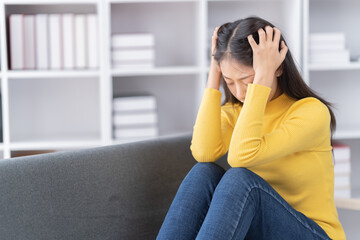 Young asian woman siting on sofa holding credit card in hand paying electronic money for shopping online.