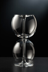 Two empty wine glasses on a black background.