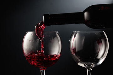 Pouring red wine into a wine glass.