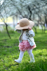 portrait of a cute little girl wearing hat in spring meadow on green grass