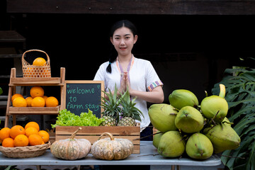 Obraz premium Indigenous Asian women raise their hands pay respect to greet tourists with a natural assortment of fruits to welcome tourists to the farm stay. Homestay in Thailand Loei