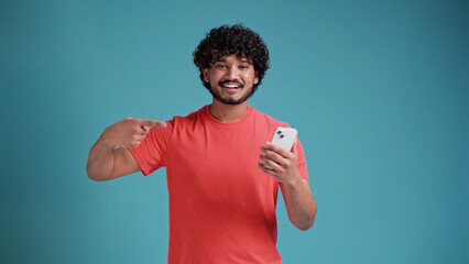 Jubilant exultant happy young bearded Indian man 20s years old hold in hand use mobile cell phone...