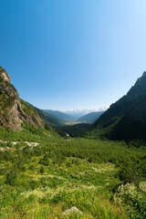 Fototapeta na wymiar Beautiful mountain landscape on the valley near the waterfall Shdugra, Mazeri, Svaneti, Georgia on a sunny bright summer day. Vertical photo