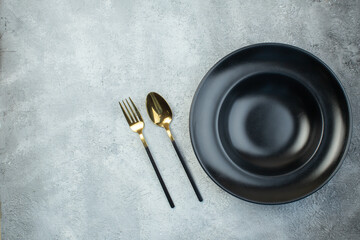 Black dinnerware set and cutlery set on isolated gray ice background with free space