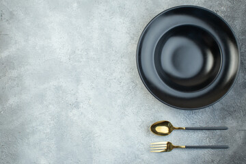 Black dinnerware set and cutlery set on the left side on isolated gray ice background with free space