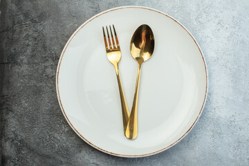 Close up shot of cutlery set on empty plate on gray background with distressed coarse-grained...