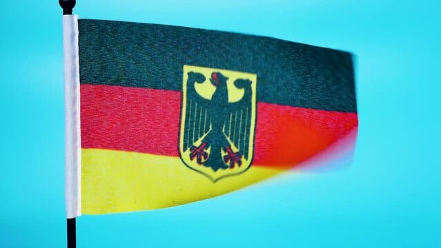 Close-up. Government flag of Germany with an eagle. The flag of germany flutters in the wind on a blue background