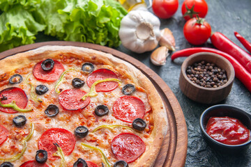 Delicious homemade pizza on wooden board tomatoes and food set on dark background