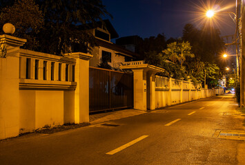 empty street at night with lamppost and fence
