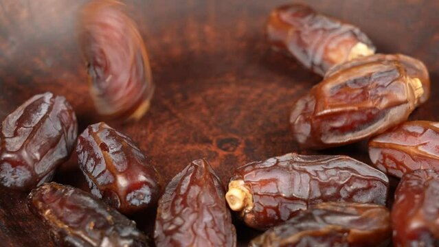 Closeup view 4k stock video footage of tasty sweet dried turkish dates isolated. Big dates slowly falling down on brown plate. Food video background