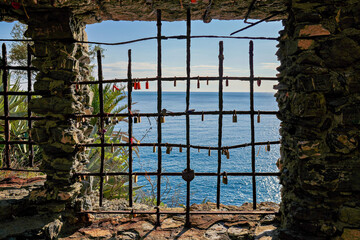 Fototapeta na wymiar rostiges Gitter am Fenster mit Vorhangschlössern dran und Blick auf das Meer