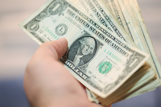 A man holding US one dollar bills. Close-up photo.
