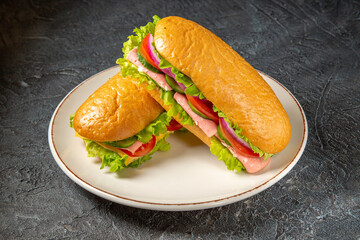 Delicious homemade sandwiches on a white plate on black distressed background with free space