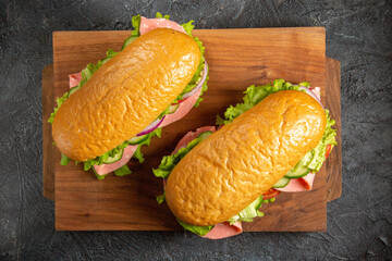 Delicious homemade sandwiches on wooden cutting boards on black distressed background