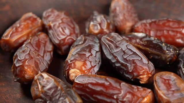 Closeup view 4k stock video footage of tasty sweet dried turkish dates isolated. Dates slowly falling down on brown plate. Food video background