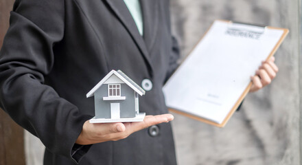 Home insurance concept and real estate. Businesswoman holding a house model working in investment about renting a house, buying a house, and home insurance