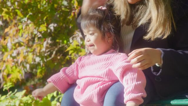 MS Mother and daughter (2-3) with Down syndrome relaxing in park
